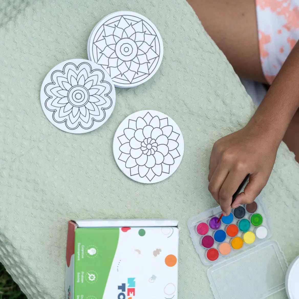 Child coloring a mandala art fridge magnet using bright colors