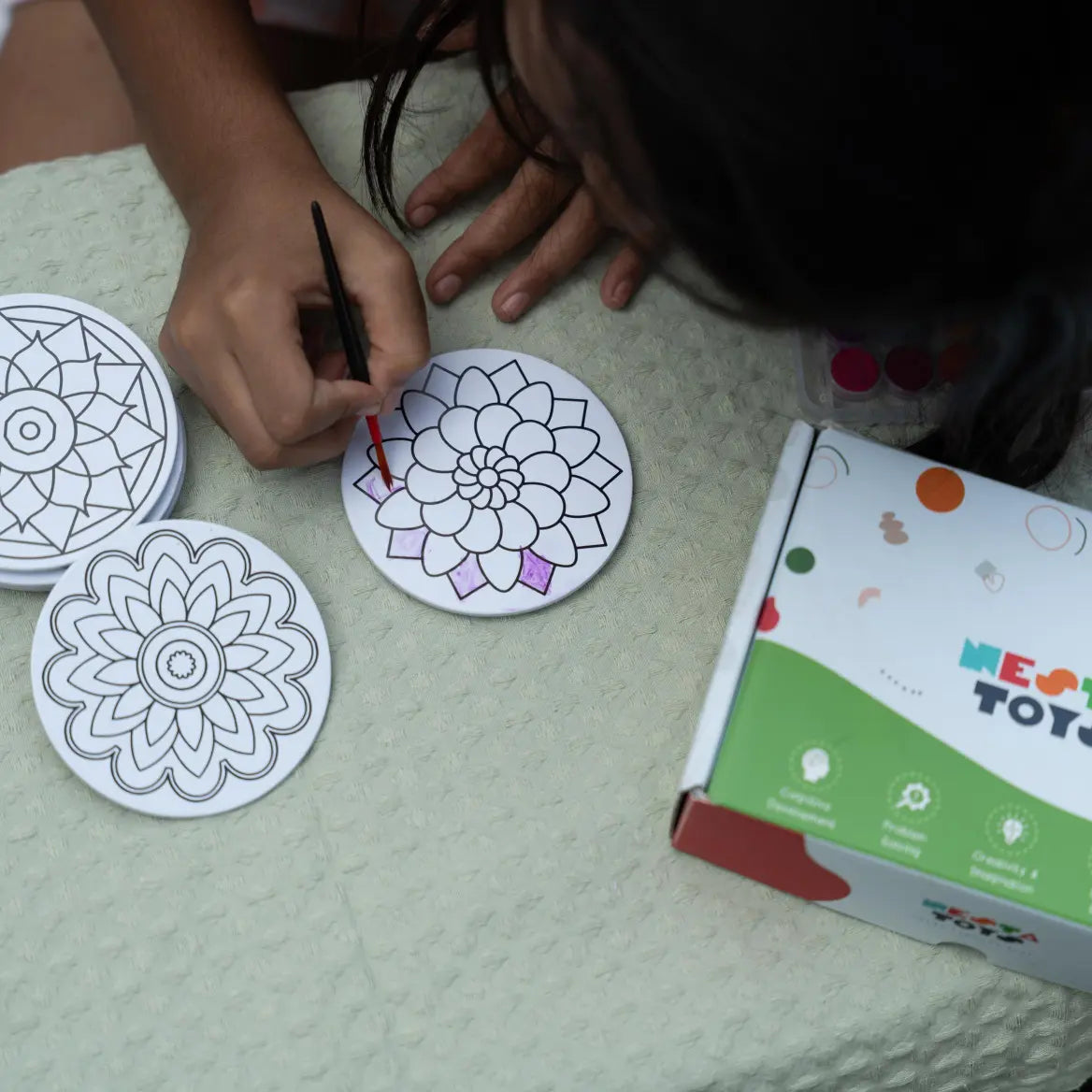 Child coloring a mandala art fridge magnet using bright colors
