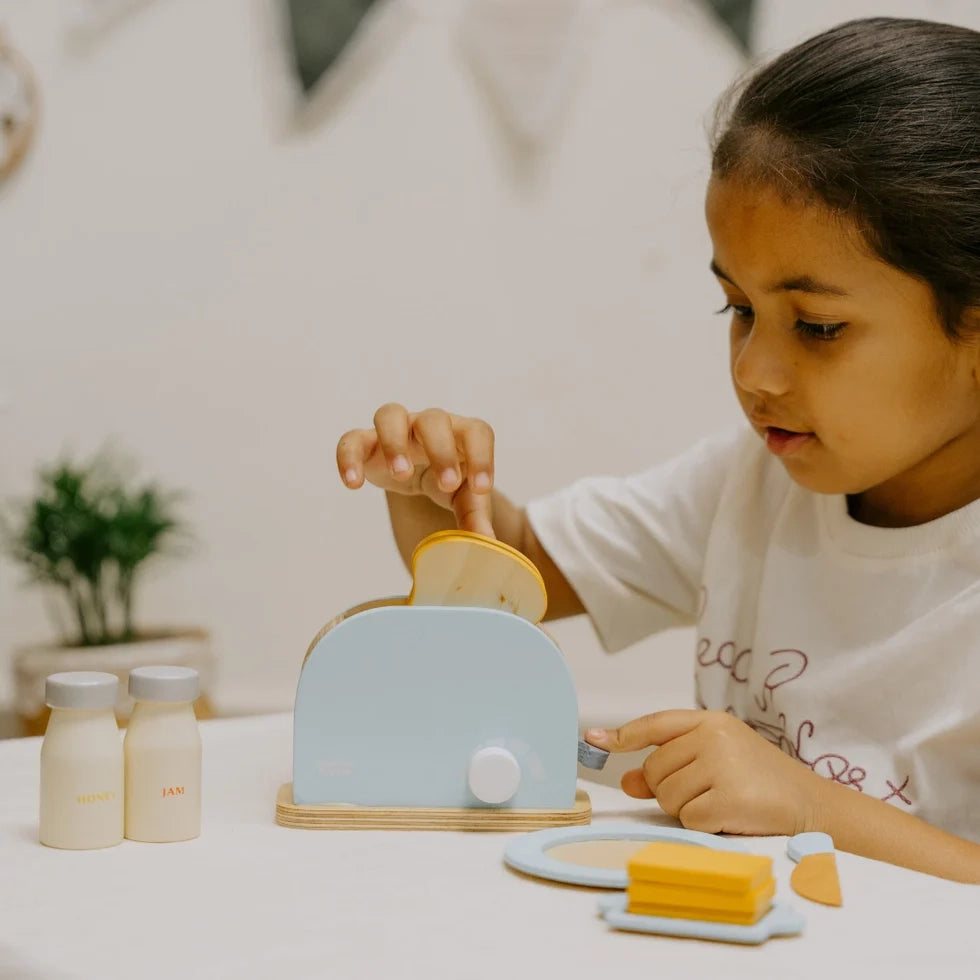 Kid playing with NESTA TOYS wooden bread pop-up toaster (blue) kitchen toy, enjoying safe pretend play and creative role-play activities.
